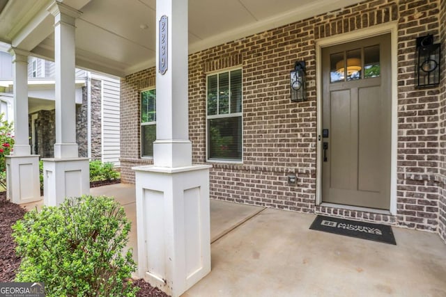 doorway to property with brick siding and covered porch