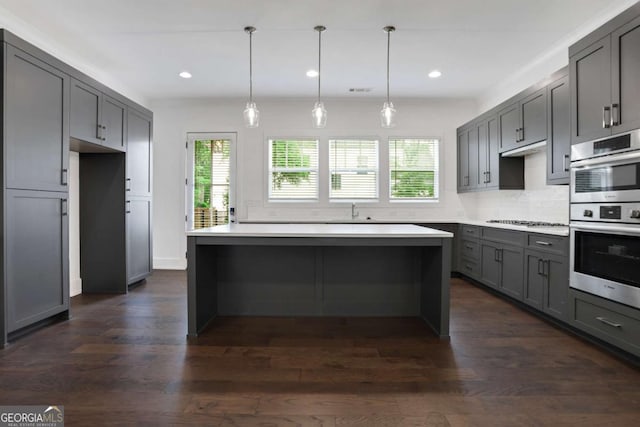 kitchen with tasteful backsplash, dark wood-type flooring, appliances with stainless steel finishes, and gray cabinets