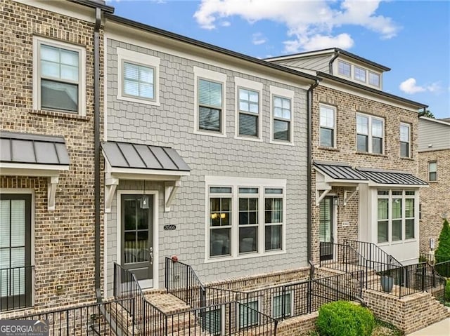 townhome / multi-family property featuring metal roof, fence, entry steps, and a standing seam roof