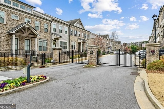 view of street with a gate, curbs, a residential view, and a gated entry