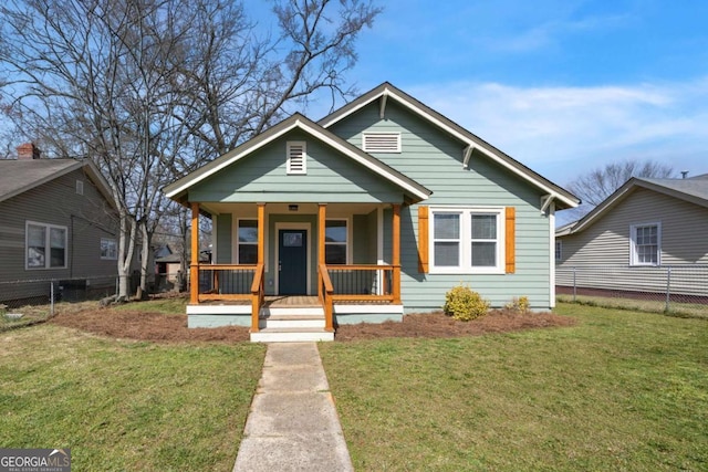 bungalow-style house with fence, covered porch, and a front yard