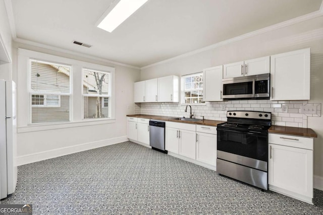kitchen with visible vents, baseboards, white cabinets, wood counters, and appliances with stainless steel finishes