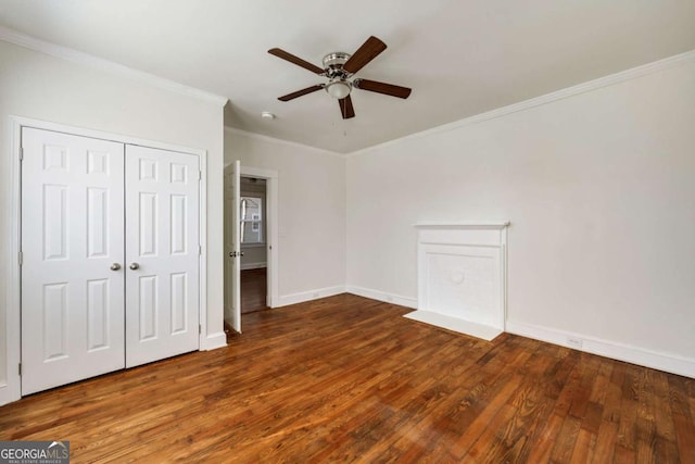 unfurnished bedroom featuring a closet, ornamental molding, wood finished floors, baseboards, and a ceiling fan