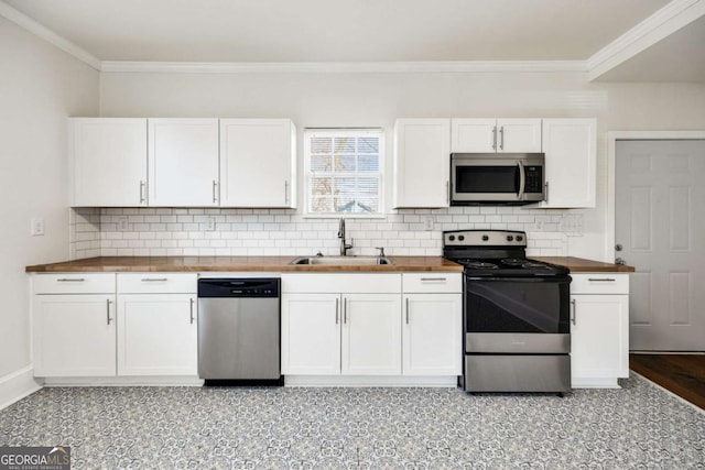 kitchen with crown molding, white cabinets, a sink, wood counters, and appliances with stainless steel finishes