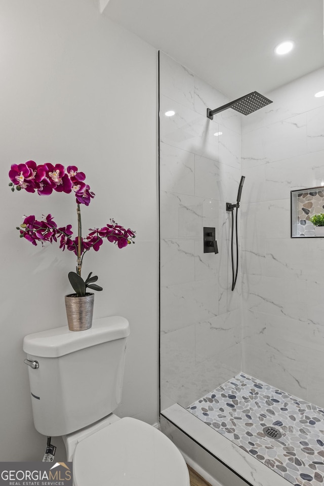 bathroom featuring a marble finish shower and toilet