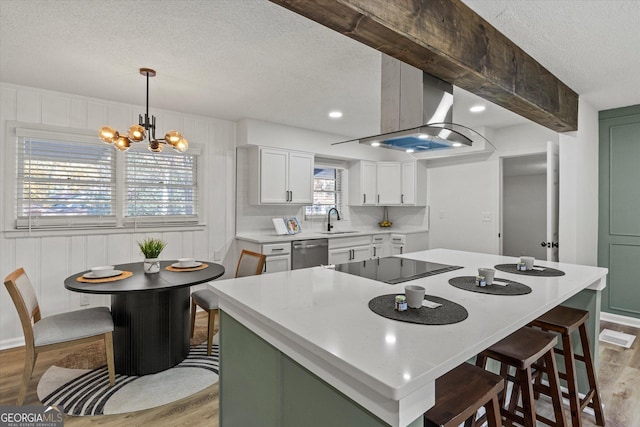 kitchen with a sink, light countertops, a textured ceiling, stainless steel dishwasher, and black electric stovetop
