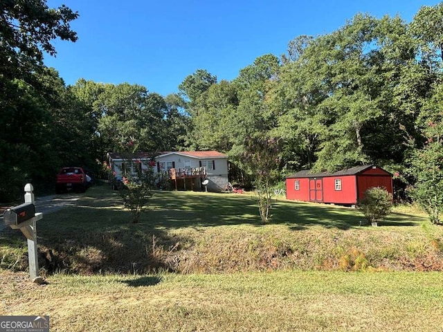 view of yard featuring a deck, an outbuilding, a storage unit, and driveway