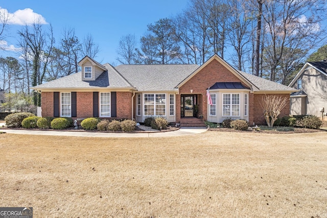 view of front of property featuring brick siding, a shingled roof, and a front lawn