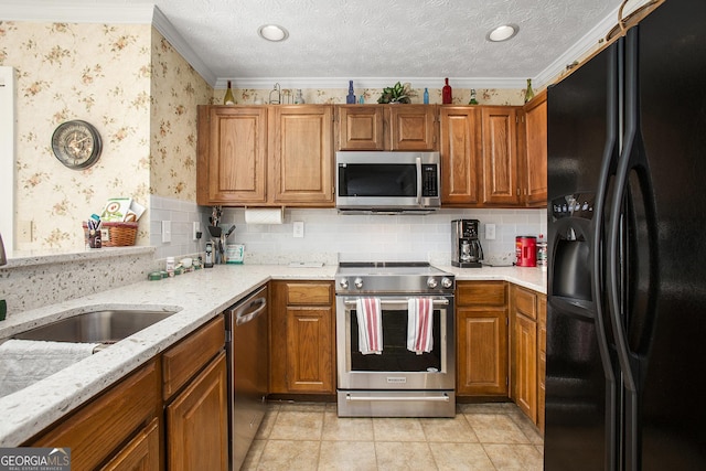 kitchen with wallpapered walls, crown molding, appliances with stainless steel finishes, brown cabinetry, and a textured ceiling