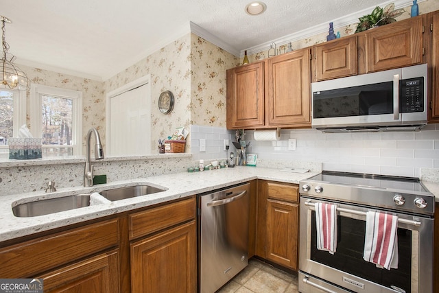 kitchen featuring brown cabinets, a sink, light stone counters, appliances with stainless steel finishes, and wallpapered walls