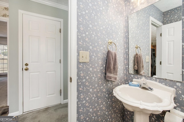 bathroom featuring wallpapered walls, crown molding, baseboards, and visible vents