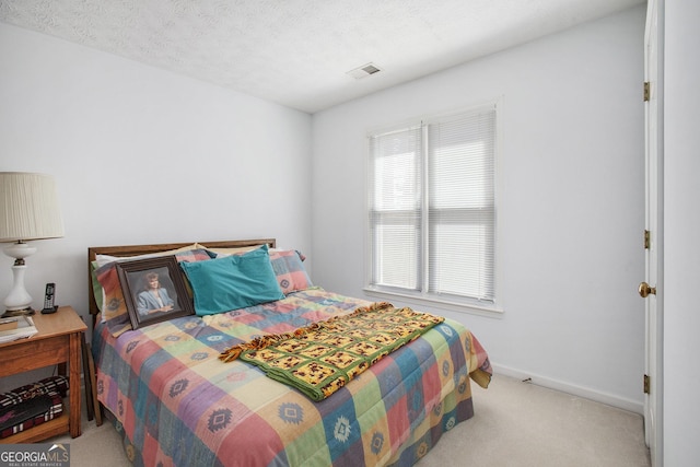 carpeted bedroom with visible vents, a textured ceiling, and baseboards