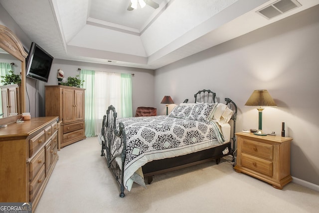 bedroom featuring baseboards, visible vents, a tray ceiling, ceiling fan, and light carpet