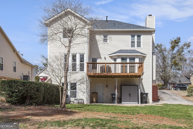 back of house with a wooden deck, central AC, roof with shingles, a lawn, and a chimney