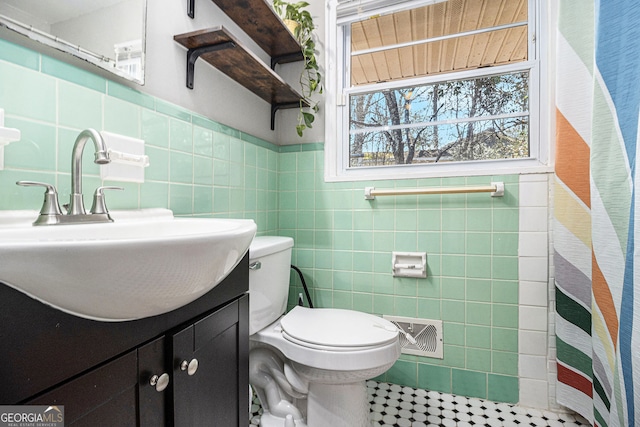 bathroom with visible vents, toilet, vanity, a shower with curtain, and tile walls