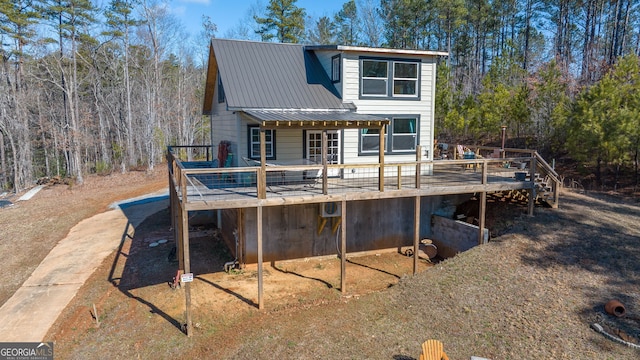 rear view of property featuring a wooden deck and metal roof