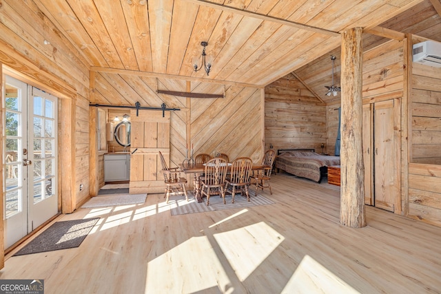 unfurnished dining area featuring wood finished floors, lofted ceiling, wood walls, a barn door, and wooden ceiling