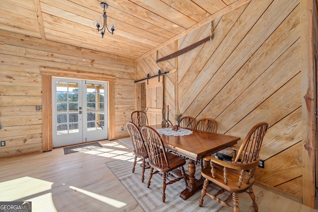 dining room featuring wood walls, french doors, wooden ceiling, and a barn door