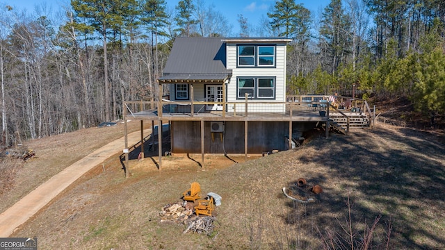 rear view of house featuring a deck, stairway, a forest view, and metal roof