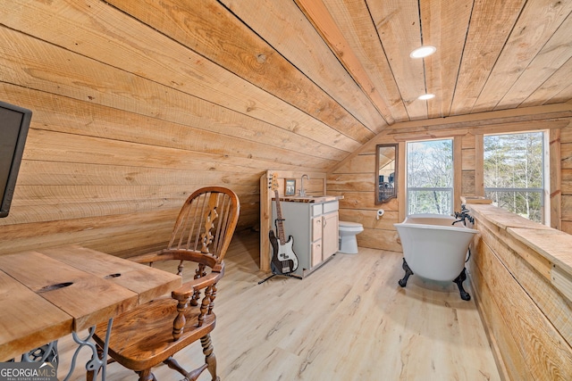 interior space with wood walls, a freestanding bath, wooden ceiling, wood finished floors, and a sink