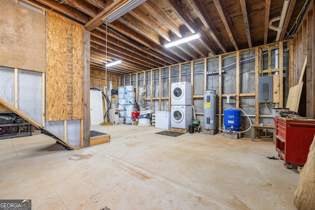 unfinished below grade area featuring electric panel, stacked washer / drying machine, and electric water heater