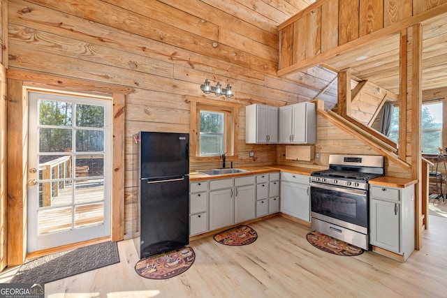 kitchen with freestanding refrigerator, light wood-style floors, plenty of natural light, stainless steel gas range, and a sink