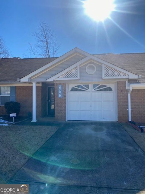 ranch-style house with brick siding, a garage, and driveway