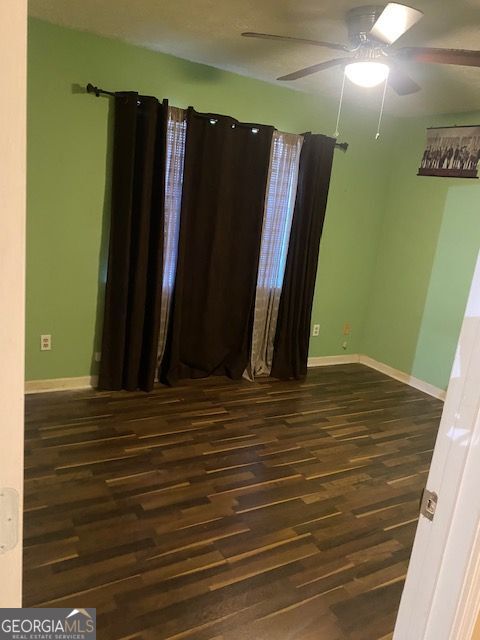 unfurnished room featuring wood finished floors, baseboards, and ceiling fan