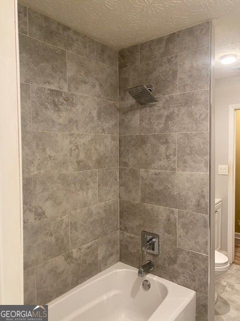 bathroom with a textured ceiling, bathing tub / shower combination, and toilet