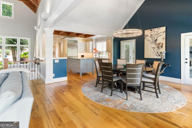 dining room with decorative columns, light wood-type flooring, and a wealth of natural light