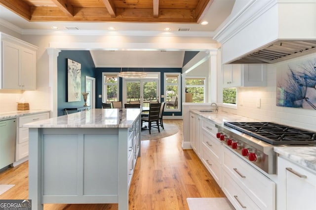 kitchen featuring light wood finished floors, a kitchen island, premium range hood, white cabinets, and stainless steel appliances