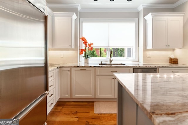 kitchen with a sink, crown molding, light wood-style floors, and stainless steel built in refrigerator