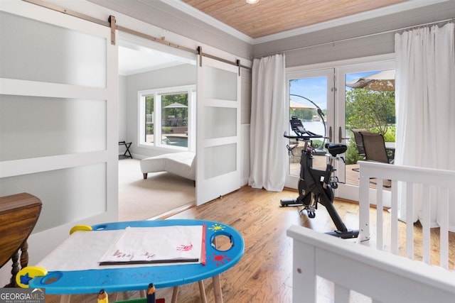 exercise area with a barn door, wood finished floors, wood ceiling, and ornamental molding