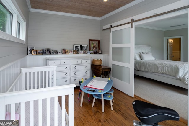 bedroom with a barn door, wood ceiling, wood finished floors, and ornamental molding