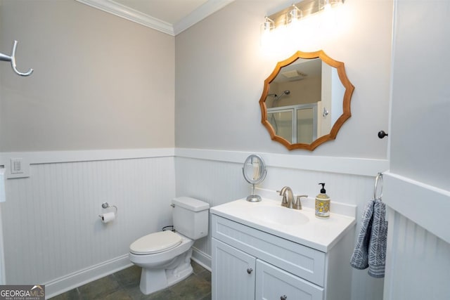 bathroom with vanity, crown molding, toilet, and a wainscoted wall