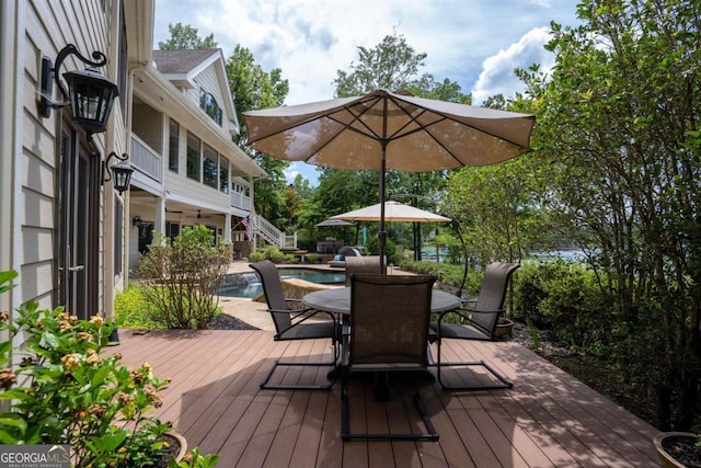 deck featuring stairs, outdoor dining area, and an outdoor pool