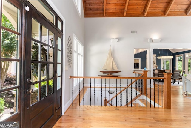 corridor with visible vents, an upstairs landing, beam ceiling, wood finished floors, and wooden ceiling