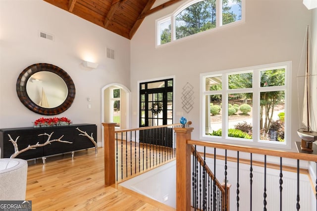 hallway with light wood-style flooring, an upstairs landing, wood ceiling, and visible vents