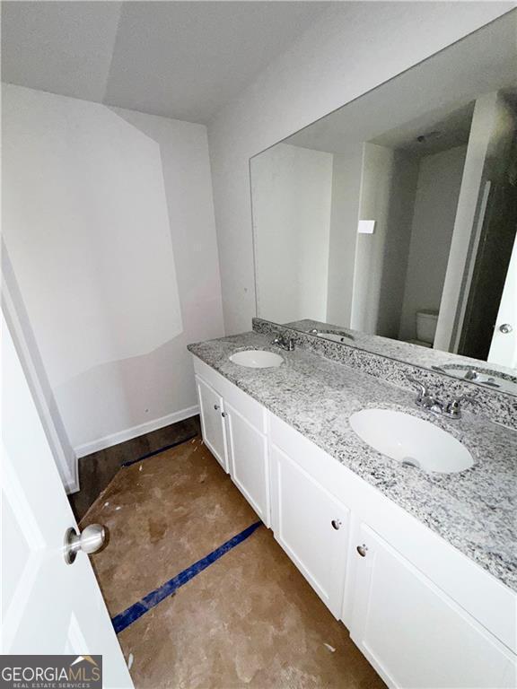bathroom featuring a sink, toilet, and double vanity