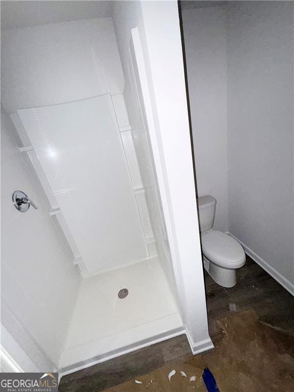 bathroom featuring a shower stall, toilet, and baseboards