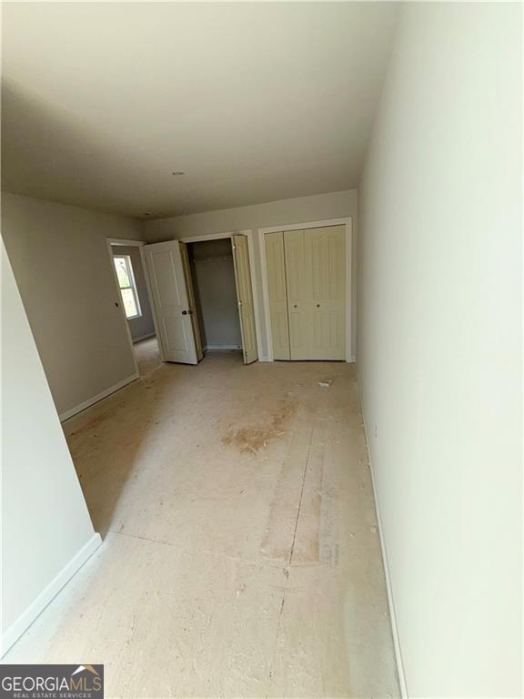 unfurnished bedroom with baseboards and multiple closets