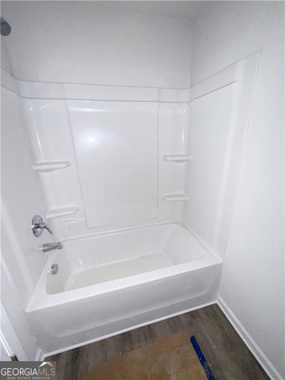 bathroom featuring bathtub / shower combination, wood finished floors, and baseboards