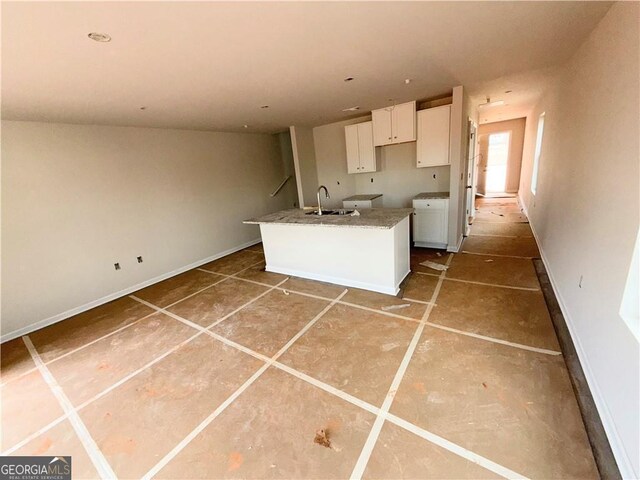 kitchen with white cabinets, a center island with sink, and a sink