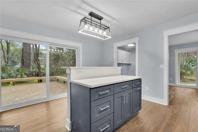 kitchen with a healthy amount of sunlight, gray cabinetry, wood finished floors, and light countertops