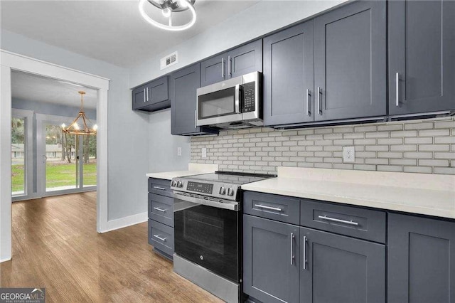 kitchen with light countertops, backsplash, wood finished floors, and appliances with stainless steel finishes