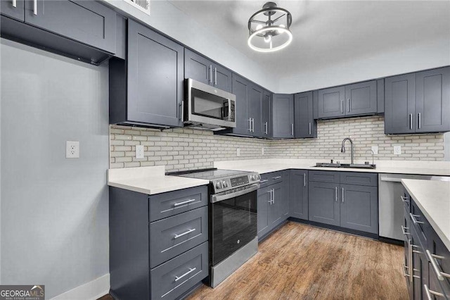 kitchen featuring light countertops, wood finished floors, appliances with stainless steel finishes, and a sink