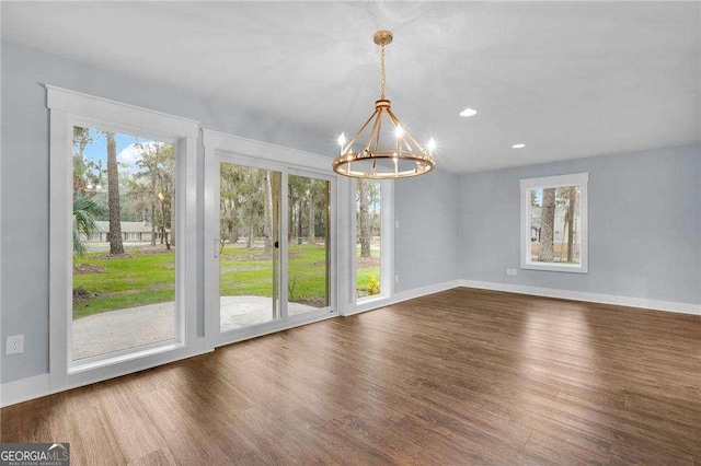 unfurnished dining area with baseboards, dark wood-type flooring, and an inviting chandelier