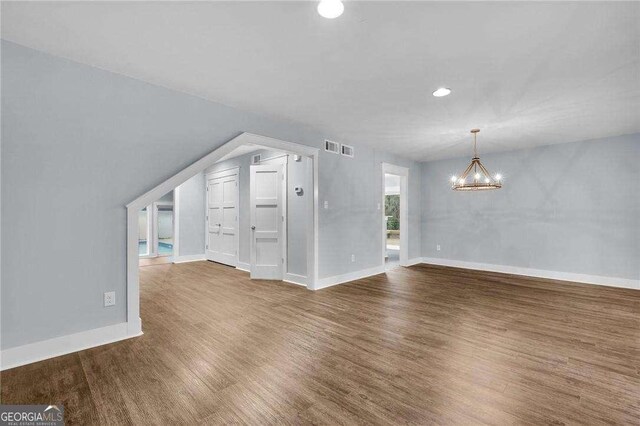 bonus room featuring a chandelier, visible vents, baseboards, and wood finished floors