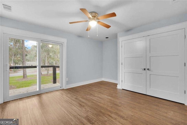 unfurnished bedroom featuring visible vents, access to outside, wood finished floors, baseboards, and ceiling fan