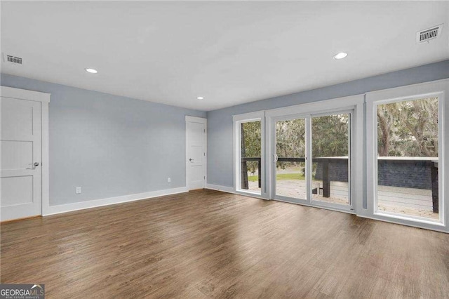 unfurnished living room featuring wood finished floors, visible vents, and baseboards